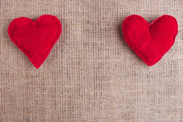 Valentijnsdag achtergrond met twee rode stof harten op sackclot — Stockfoto