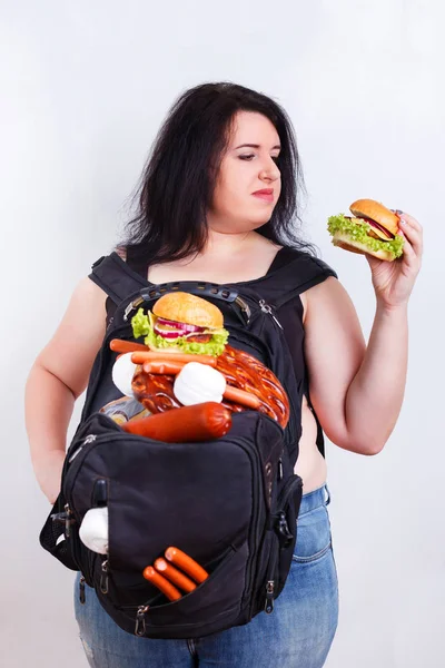 Mujer joven gorda obesa con una gran mochila llena de comida chatarra en —  Fotos de Stock