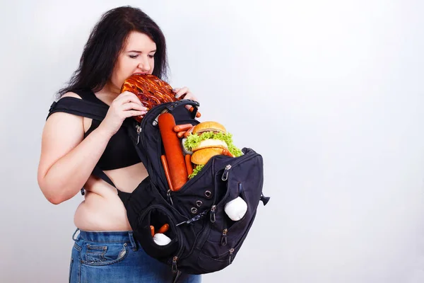 Mujer joven gorda obesa con una gran mochila llena de comida chatarra en —  Fotos de Stock