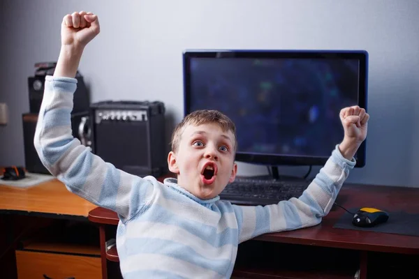 Gana el juego. Feliz niño jubiloso jugando juego de ordenador en su ro —  Fotos de Stock