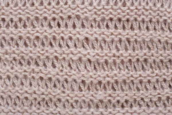 Knitted texture of beige woolen fabric with pattern. Copyspace,