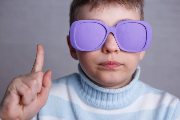 Cute boy in violet sunglasses with opaque lenses pointing upward — Stock Photo, Image