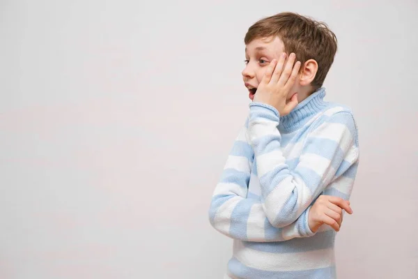 Söt förvånad eller chockad pojke i en tröja på vit bakgrund, — Stockfoto