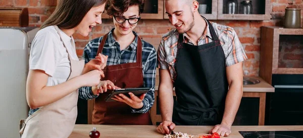 Giovani allegri e sorridenti che leggono la ricetta su tablet pc. Amico. — Foto Stock