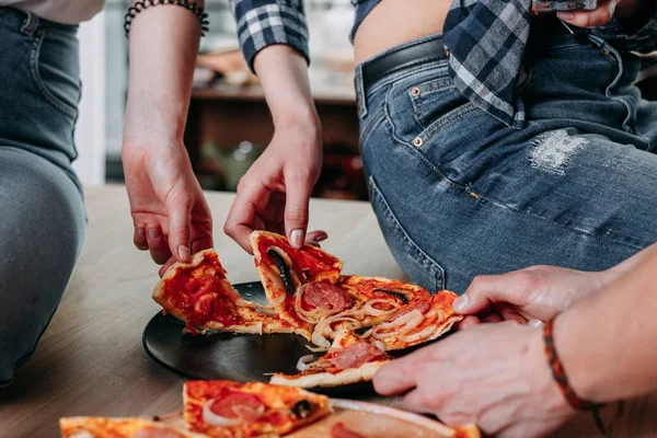 People picking up pizza slices from the plate