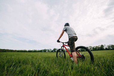 Adam binicilik bisiklet üzerinde bir çayır yeşil çim ile