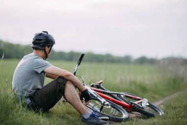 Yol kenarında bisiklet ile istirahat kask içinde adam