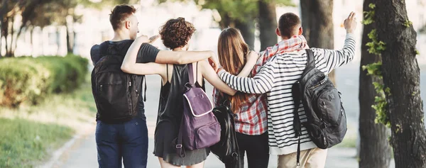 friends with backpacks hugging walking in the city