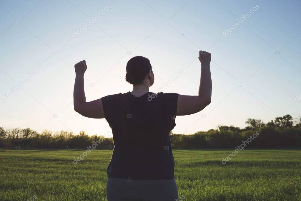  Overweight woman celebrating rising hands to sky