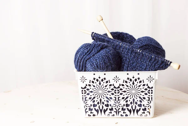 Blue knitting wool balls in wicker basket on white