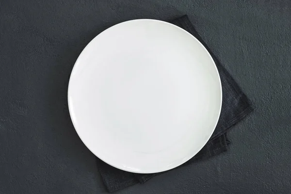 Empty plate on dark stone background.