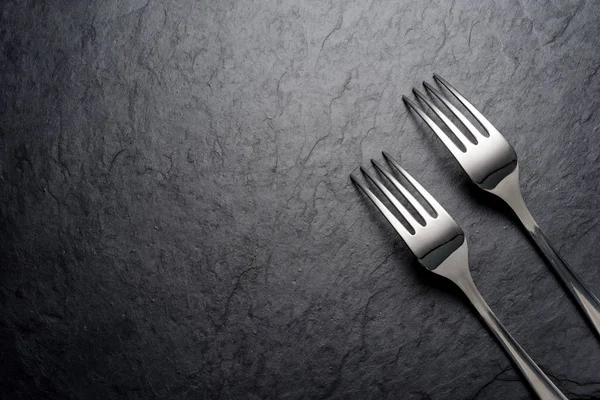 Two forks on dark black slate background — Stock Photo, Image