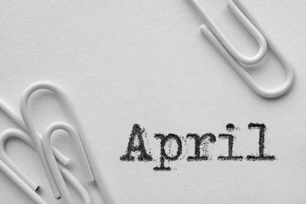 Белые пластиковые скрепки со словом "апрель" — стоковое фото