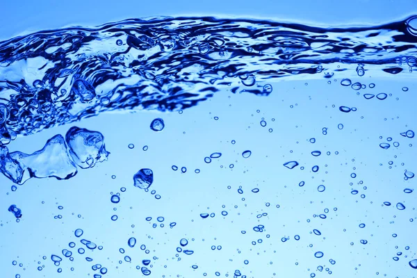 Luftblasen unter blauem Wasser und Wellen oder Spritzen — Stockfoto