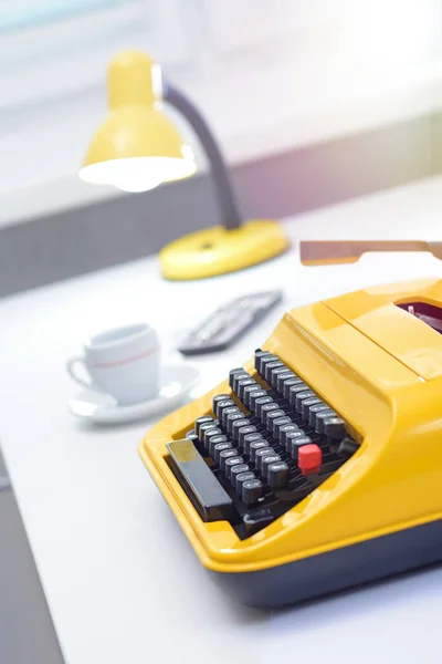 Yellow typewriter with lamp and coffee on white office desk — ストック写真