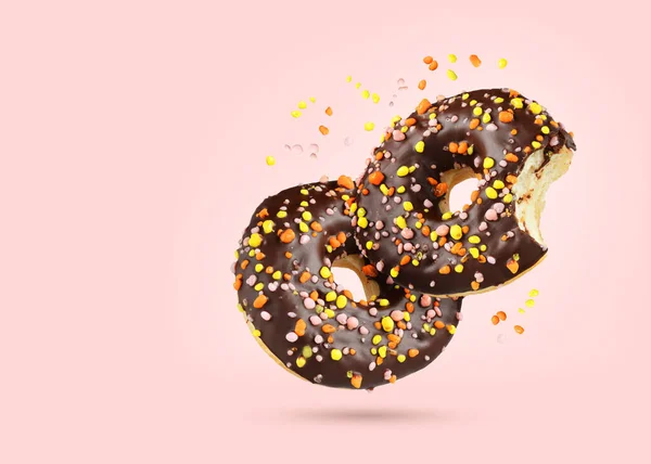 Dois Donuts Voadores Chocolate Com Diferentes Cores Polvilhas Fundo Rosa — Fotografia de Stock