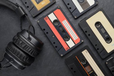 Kulaklıklı siyah kulaklıklar ve arka planda ses bandı küçük kasetler