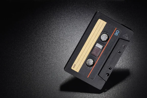 Audio tape. Old black compact cassette on dark background. Copy space