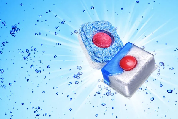 Dishwasher detergent tablets under blue water with bubbles of air