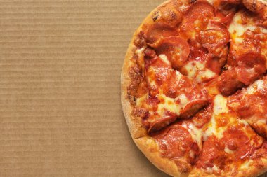 Kahverengi lifli arkaplanda pizza pepperonisi ve metin için kopya alanı.