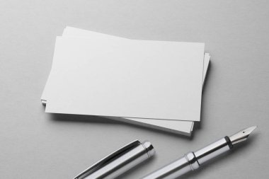 Beyaz desenli kağıt arka planda dolmakalem ile kartvizit yığınının bir kopyası