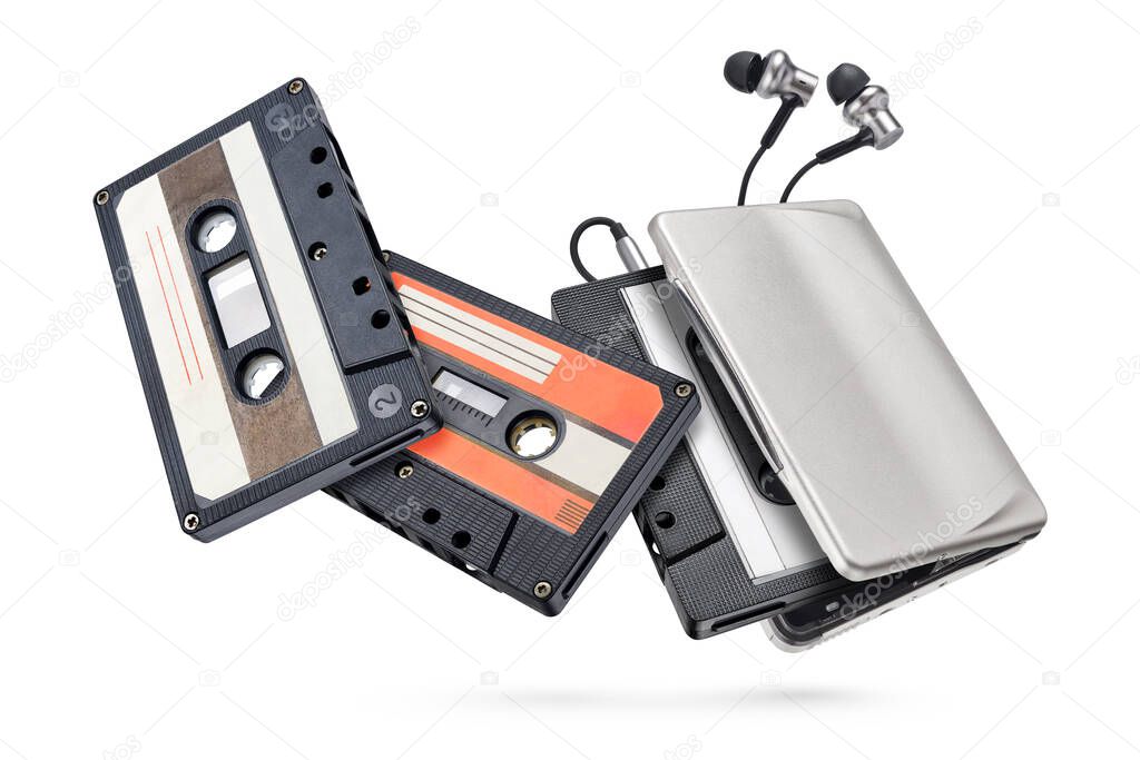 Metallic portable player with earbuds and audio cassette tapes isolated on white background