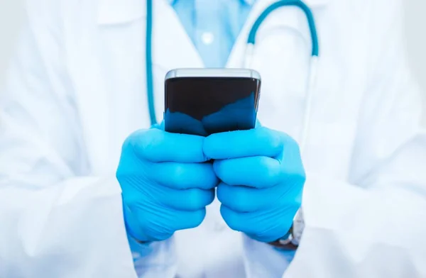 Arzt spielt Smartphone — Stockfoto