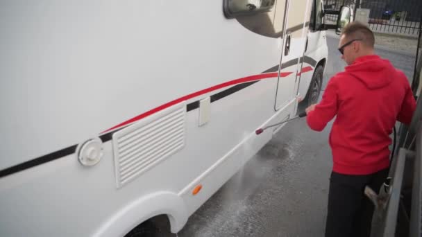 Caucásico hombres en su 30s limpieza fuera de su caravana autocaravana utilizando la presión lavadora . — Vídeo de stock