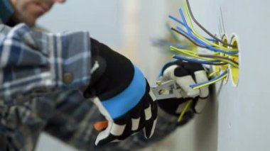 Elektrikçi prizdeki kabloları kesiyor. Elektrik Eklentisi Yüklemeye Hazırlanıyor. 