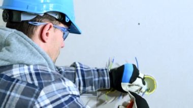 Elektrik tesisatı üzerinde çalışan elektrikçinin yakın çekimi. Kablolar yerleştirme için sıralanıyor ve hazırlanıyor. 