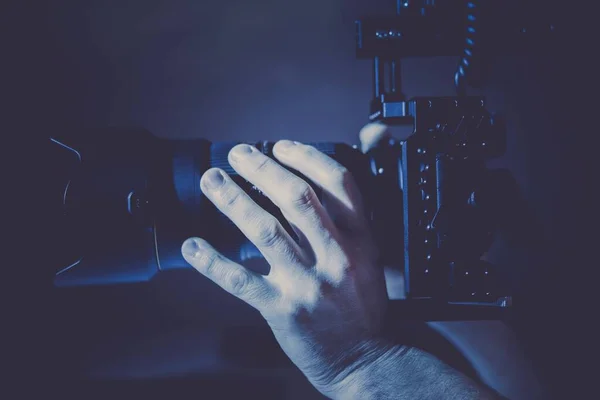 在深蓝色发光的地方手握数码相机拍照的男子 — 图库照片