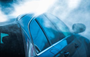 Siyah yolcu arabasının spreylendiği, durulandığı ve otomatik oto yıkama servisinden geçtiği yakın plan.. 