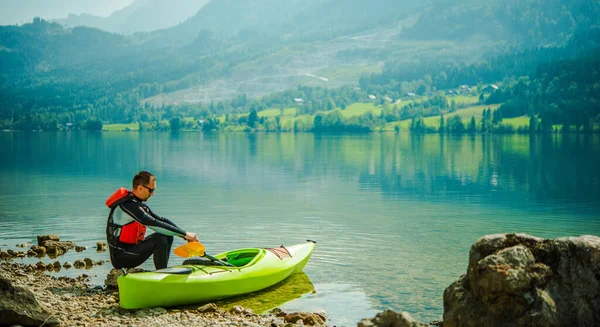 白种人坐在湖边休息 赛后独木舟 — 图库照片