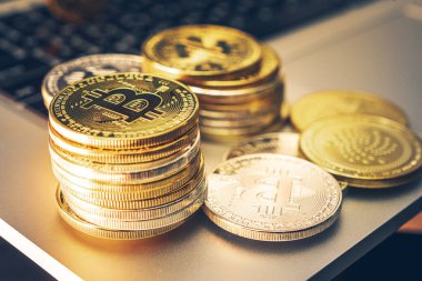 Bitcoin Şifreleme Para Birimi Bilgisayar klavyesinin yanındaki masaya düzgünce istiflenmiş altın paralar tarafından sunulmaktadır.
