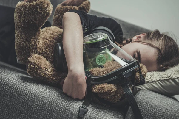 Jovencita Durmiendo Sofá Sosteniendo Protegiendo Oso Peluche Usando Máscara Gas — Foto de Stock