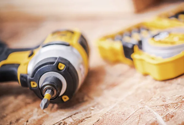 Close Up Of Cordless Black And Yellow Power Drill And Plastic Yellow Box With Set Of Drill Bits.