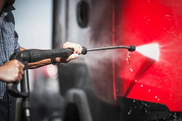 洗車場でセルフサービス機器を使用したレッドセミトラックの外装をスプレーする男のクローズアップ — ストック写真