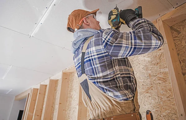 電気ドリルドライバと白人建設請負業者は 家の天井にドリウォール要素を添付します 仕上げ インテリア — ストック写真