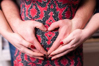 Çift el yapmak kalp simgesi hamile karnına