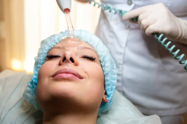 Tratamiento de belleza facial. Mujer recibiendo terapia facial Darsonval usando D 'Arsonval de alta frecuencia, dispositivo de cuidado de la piel para un punto anti —  Fotos de Stock