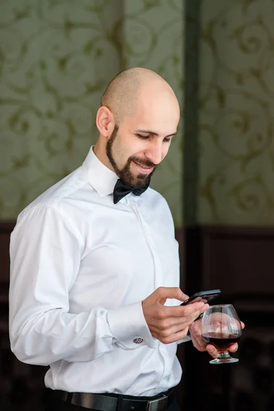 A bald man speaks on the phone in the restaurant.