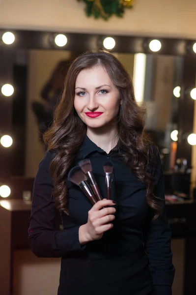 Beautiful girl makeup artist near mirrors — Stock Photo, Image