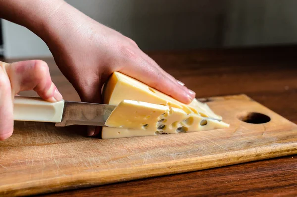 Cortar queso en una tabla de madera . — Foto de Stock