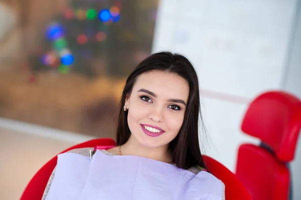 Schönes Mädchen lächelt im Zahnarztstuhl. — Stockfoto