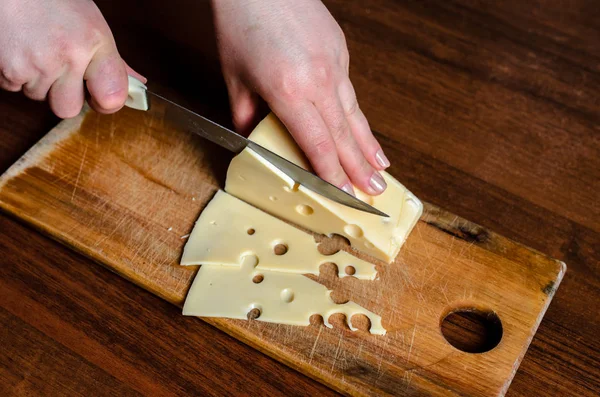 Cortar queso en una tabla de madera . — Foto de Stock