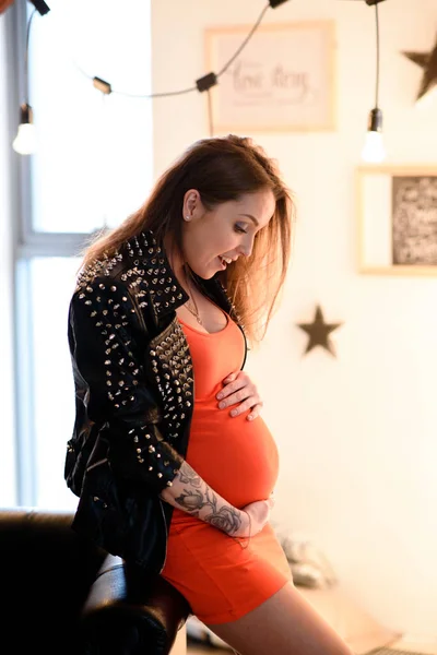 Dziewczyna w ciąży z tatuażem w czerwonej sukience. — Zdjęcie stockowe