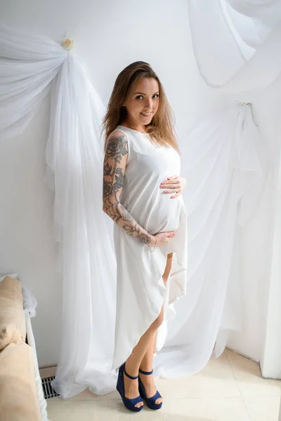 Menina grávida com tatuagem em um vestido branco . — Fotografia de Stock