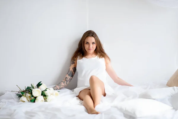 Chica embarazada con tatuaje en un vestido blanco . —  Fotos de Stock