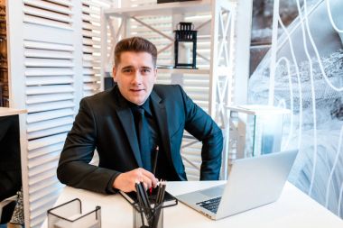Güzel ofis dizüstü çalışan ve gülümseyen iş adamı..
