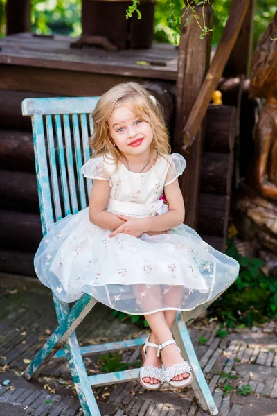 Aranyos kis baba lány gyönyörű fehér ruhában, a játszótér, pihenőpark stump széken ülő — Stock Fotó